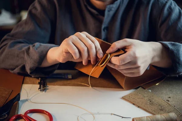 Ayakkabı atölyesinde çalışan genç bir zanaatkarın özel deri ayakkabılar üretmesi.