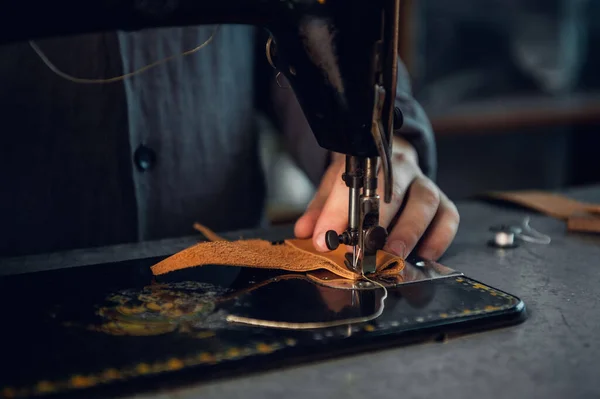 A piece of genuine leather is sewn by a tailor on a sewing machine. Neat seam