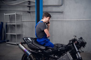 Bir işçi bisiklette oturmuş müşteriyi arıyor.