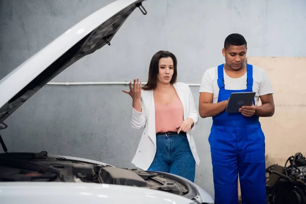 Kobieta wynajmuje mechanika w kombinezonach do naprawy samochodu — Zdjęcie stockowe