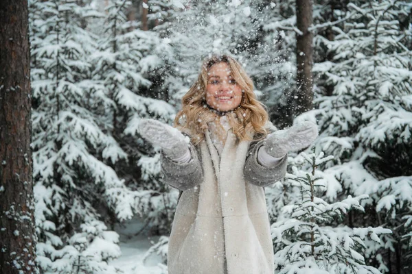 Счастливая блондинка в рукавицах с горсткой снега. Портрет на открытом воздухе зимой. — стоковое фото
