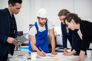 İnşaat ekibi bir AR üzerinde pusula ve planlarla çalışıyor.