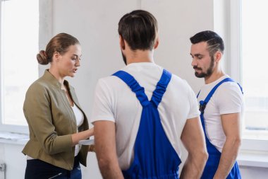 Kadın müşteri inşaatçılarla iş hakkında konuşuyor