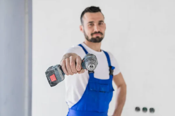 Bearded handyman visar en borr till kameran — Stockfoto