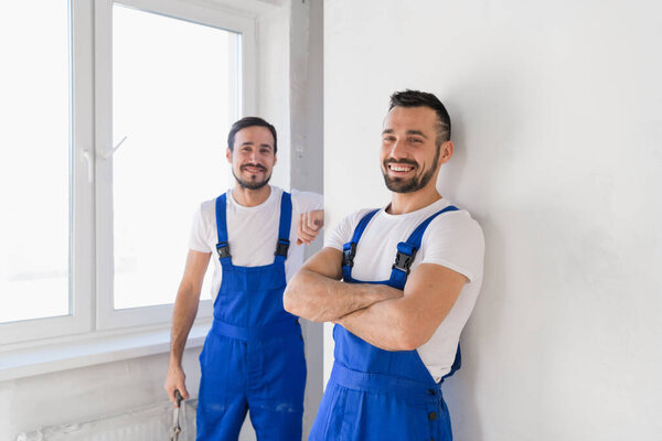 Два дружественных строителя в комбинезоне улыбаются