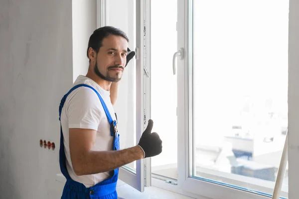 Trabalhador masculino instala uma janela e mostrando o polegar — Fotografia de Stock