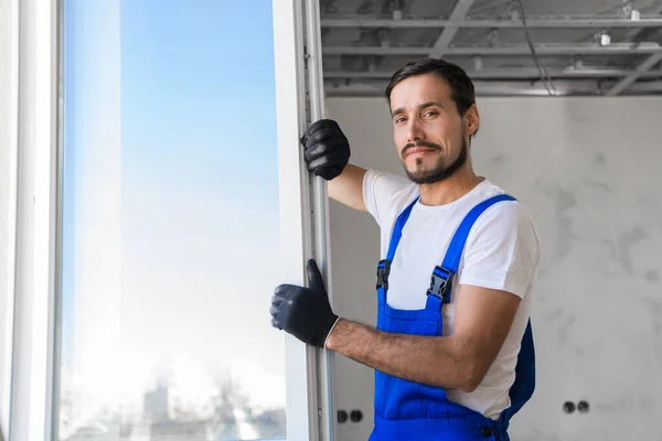 Reparatör i handskar installerar fönstret i rummet — Stockfoto