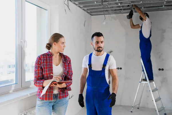 Ein Kunde spricht mit einer Reparaturfirma in Uniform und macht sich Notizen in einem Notizbuch — Stockfoto