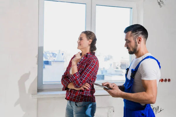 The workman, together with the customer, inspects the apartment and writes in a notebook — Foto de Stock