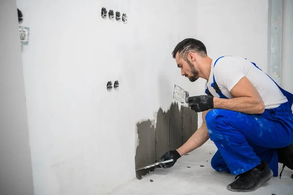 Constructor en overoles pone azulejos en la pared del baño — Foto de Stock