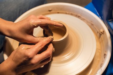 Çömlekçi çarkında, genç bir çömlekçi kilden demlik hazırlıyor..