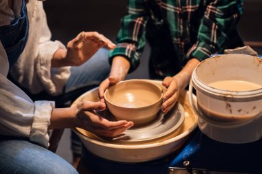 Ablası ve küçük erkek kardeşi çömlek atölyesinde kil tabakları yaparak vakit geçiriyorlar..