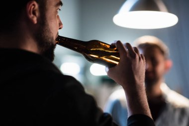 Arkadaşlar garajdaki bekarlığa veda partisinde bir partide siyah şişelerden bira içiyorlardı..