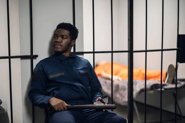 Un carcelero guarda celdas con prisioneros sentenciados a cadena perpetua en uniformes naranjas. — Foto de Stock