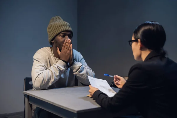 A black guy listens to his rights from a civil lawyer at a table in a visiting room in a state prison