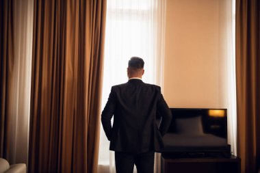 Klasik takım elbiseli bir işadamı ayakta duruyor ve ona bakıyor.