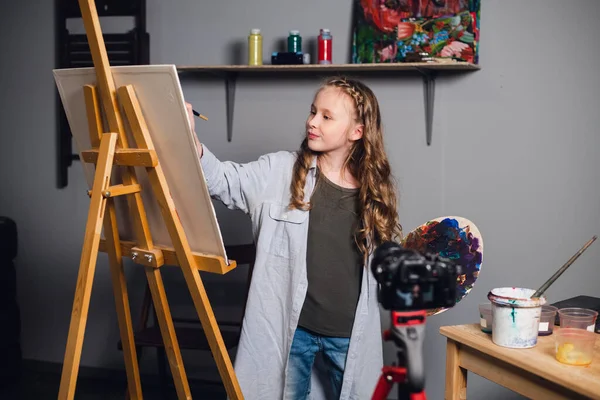 Una linda artista adolescente está grabando una historia para su video blog en un taller en una escuela de arte. — Foto de Stock
