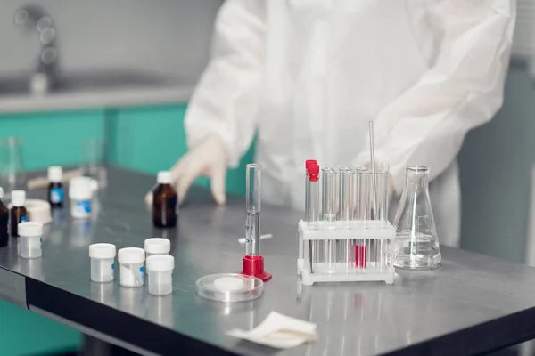 Os cientistas colocam as mãos na mesa do laboratório. Laboratório químico em acção. Uma imagem de perto da mesa com os clínicos mãos enluvadas e alguns copos de laboratório — Fotografia de Stock