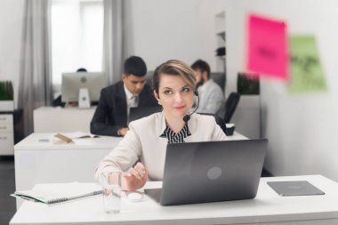 Ofiste çalışan genç bir kız yönetici dizüstü bilgisayarla şirketin bir müşterisiyle iletişim kuruyor..