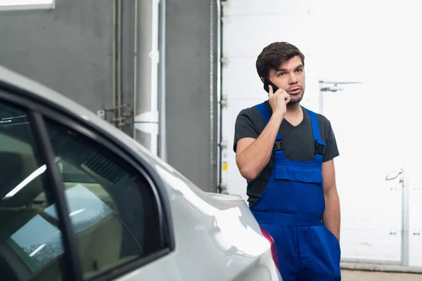 Brodaty mechanik rozmawiający przez telefon z klientem — Zdjęcie stockowe