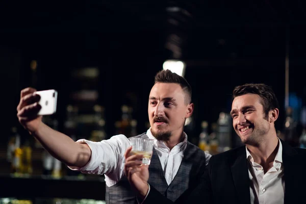 Двоє друзів зустрічаються в барі і беруть селфі на свій смартфон — стокове фото