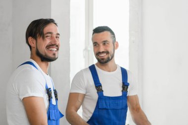 Üniformalı iki inşaat işçisi gülümsüyor