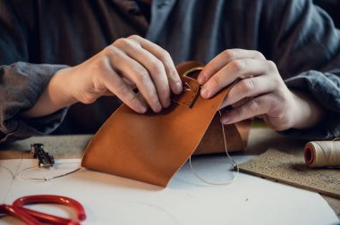 Deneyimli bir tabakçı dikişli deri bir ürün için toka diker.