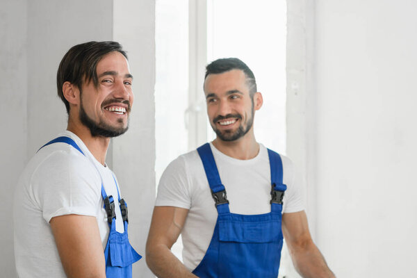 Двое строителей в форме улыбаются