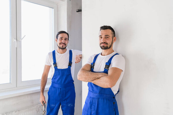 Двое мужчин в комбинезоне смотрят в камеру.