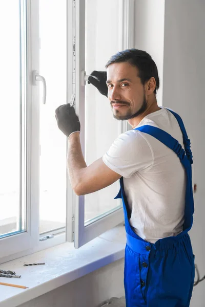 Builder installs the window and looks at the camera — Stock Photo, Image