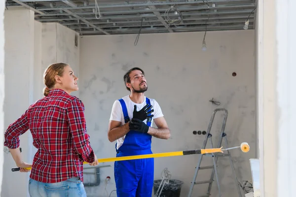 Mujer ayuda a capataz pintar paredes con rodillo de pintura — Foto de Stock