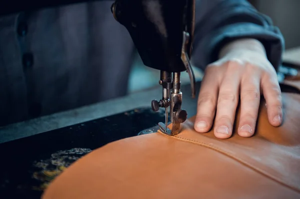 El proceso de coser dos piezas de cuero genuino por un zapatero en una máquina de coser especial de la vieja escuela. Puntadas de hilo y la mano del maestro — Foto de Stock