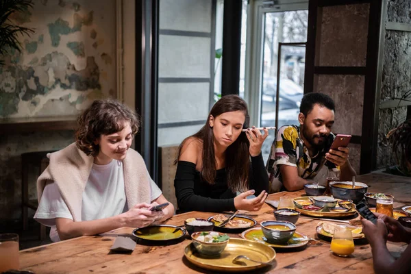 Un groupe multiculturel d'étudiants partageant la nourriture dans un café et usi — Photo