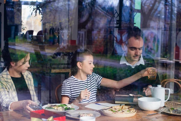 Une fille déjeunant avec ses parents, vue par la fenêtre — Photo