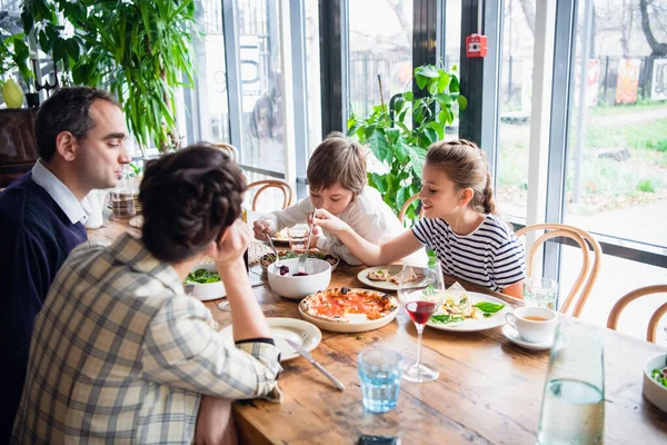 Een gezin van vier personen luncht op een ruime veranda. — Stockfoto