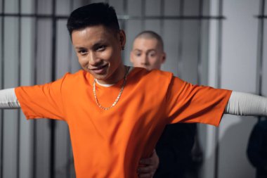 Silahlı bir muhafız, hapishane koridorunda yeni gelen bir suçluyu parmaklıkların arkasında arıyor..