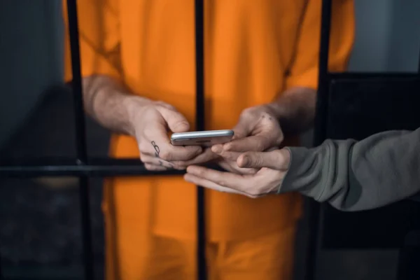 El criminal en la celda de la prisión recibió un teléfono inteligente para comunicarse con sus familiares.. — Foto de Stock