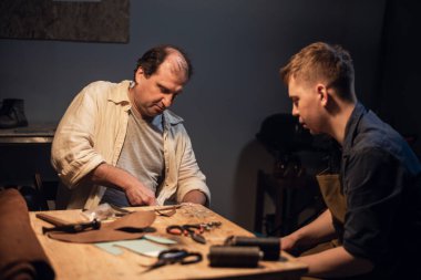 Baba ve oğul, anne için bir hediye hazırlayın. Ayakkabıcıda hevesle ayakkabı yapın..