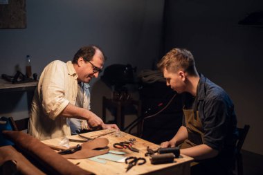 Deneyimli bir ayakkabıcı ve asistanı atölyelerinde deriden siparişe ayakkabı yapıyorlar..