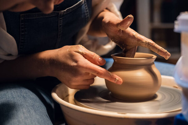 close-up of the hands of a potter when sculpting a vase from clay on a potters wheel in the workshop.