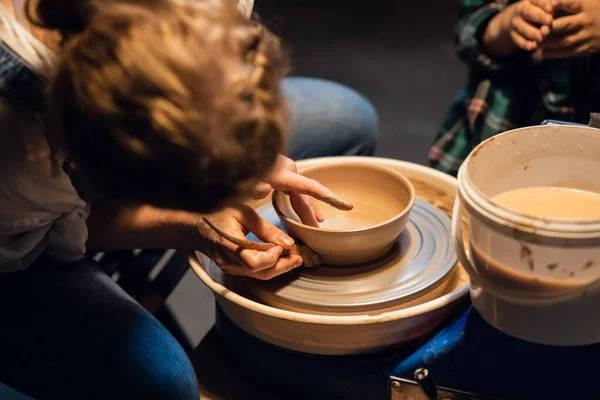 A young mother teaches her son the family pottery craft in a workshop. — Stock Photo, Image