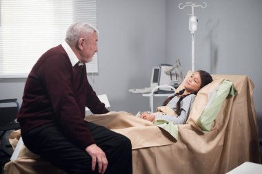 Hastane koğuşunda torununun yanında oturan son sınıf öğrencisi.