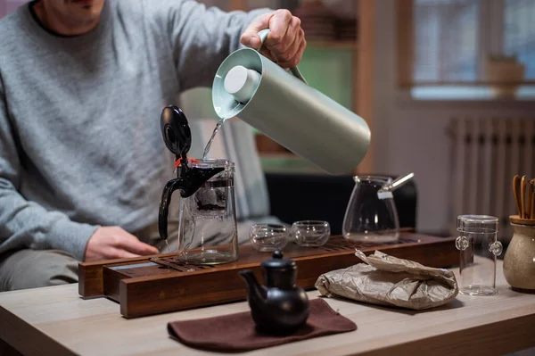 Brewing delicious strong chinese tea. Stage of a real oriental tea ceremony at home with a special set of bamboo tools. The tea master pours hot water into a bowl. — Stock Photo, Image