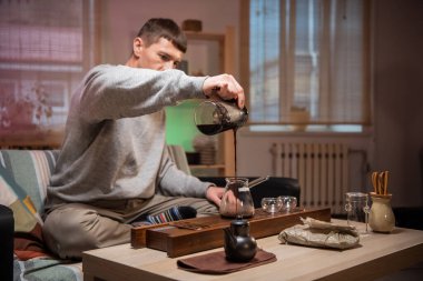 Lezzetli Çin çayı demliyorum. Gerçek bir oryantal çay seremonisi sahnesi ve bambu aletleri. Çay ustası bir kaseye sıcak su döker..