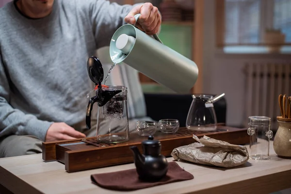 Brewing delicious strong chinese tea. Stage of a real oriental tea ceremony at home with a special set of bamboo tools. The tea master pours hot water into a bowl. — Stock Photo, Image