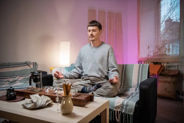 A young adult man learns the art of meditation during a tea ceremony to relax and enjoy the natural aroma of chinese black raw tea.