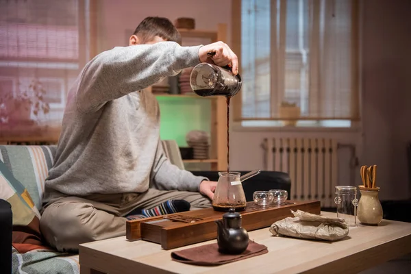 Η διαδικασία παρασκευής αυθεντικού γιαπωνέζικου τσαγιού στο σπίτι. Ένας άντρας ρίχνει ζεστό νερό σε ένα μπολ με αποξηραμένα φύλλα τσαγιού. — Φωτογραφία Αρχείου