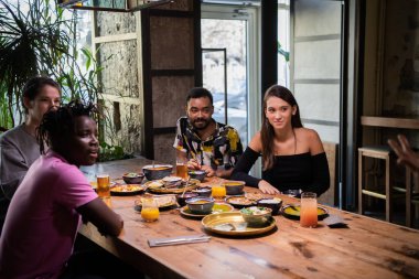 Çok kültürlü bir arkadaş grubu bir kafede vakit geçiriyor.