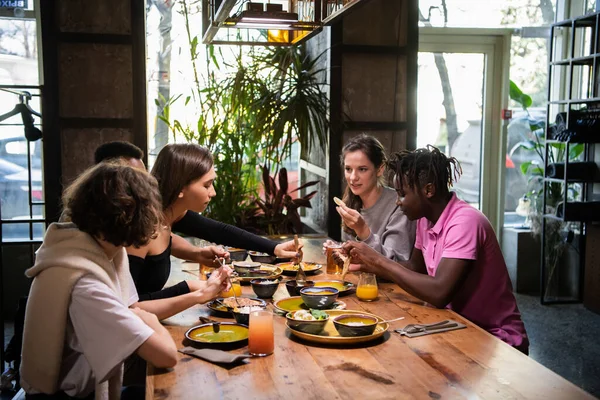 Un groupe multiculturel d'étudiants dans un café, mangeant de la nourriture asiatique, — Photo