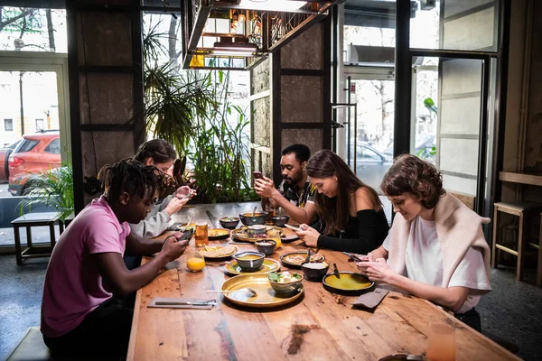 Un groupe multi-ethnique d'étudiants mangeant dans un café moderne avec fr — Photo